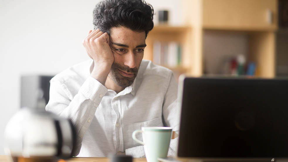 Online scams stressed man laptop